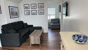A modern living room with a sectional sofa, a wooden coffee table, and a decorative bowl on a side table. - Avalon Stone Harbor - Heart of 7 Mile Island, Beach Block!! (Avalon)