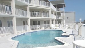 A pool area with a clear blue pool, white lounge chairs, and a white fence surrounding the pool. - Avalon Stone Harbor - Heart of 7 Mile Island, Beach Block!! (Avalon)