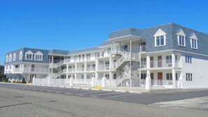 A multi-story hotel with balconies, a central staircase, and a parking lot. - Avalon Stone Harbor - Heart of 7 Mile Island, Beach Block!! (Avalon)