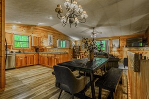 A spacious kitchen with wooden cabinets, a dining area with a table and chairs, and a ceiling fan.