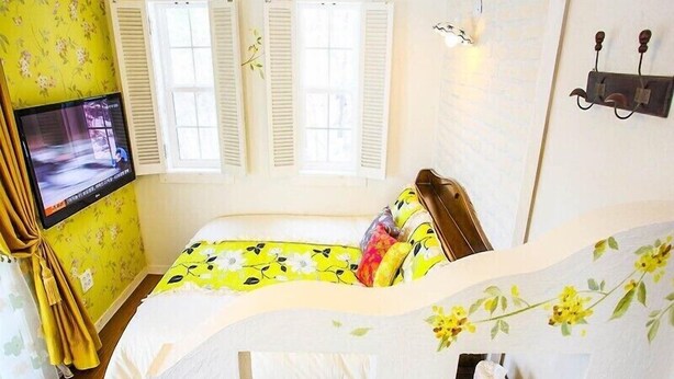 A bedroom with a bed, a television, and a window with shutters. - Wind Garden Pension (Buan)