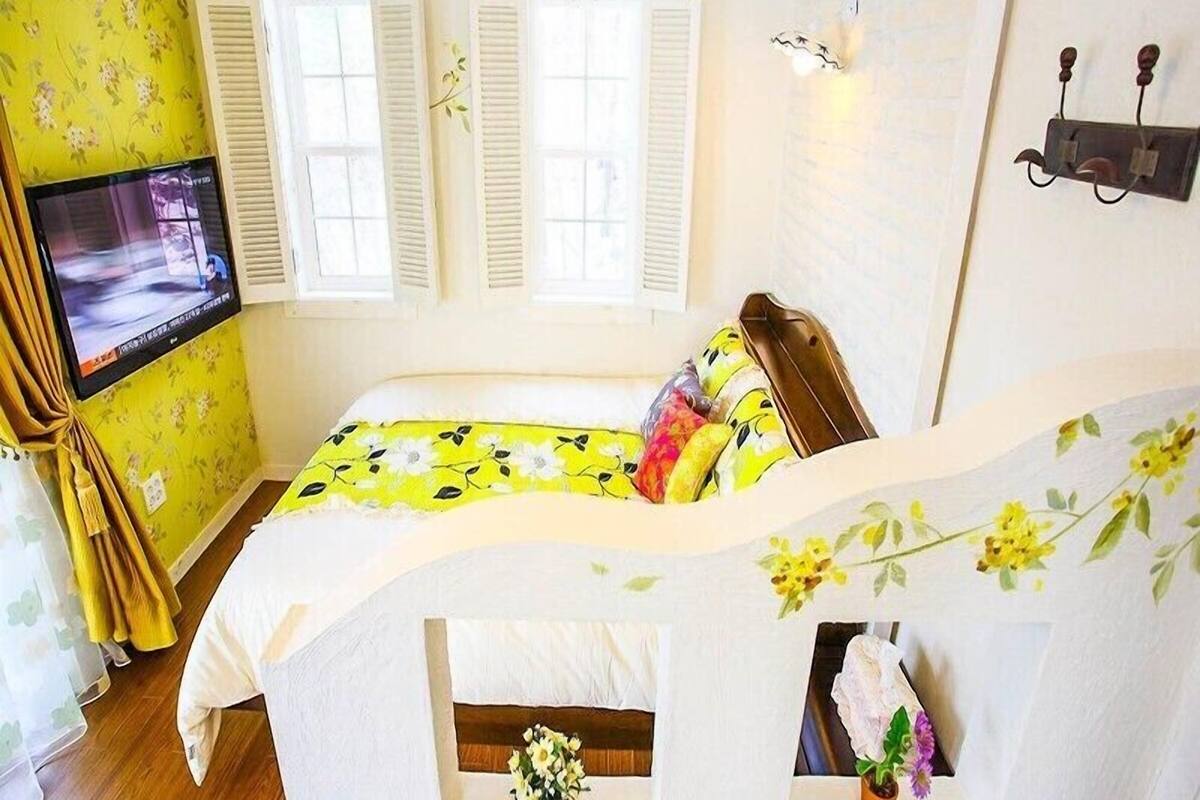 Une chambre à coucher avec un lit, une télévision et une fenêtre avec des volets.