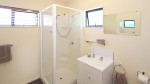 A bathroom with a glass-enclosed shower, a white sink, a mirror, and a towel rack.