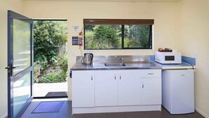 A compact kitchen with a sink, a kettle, a microwave, and a refrigerator.