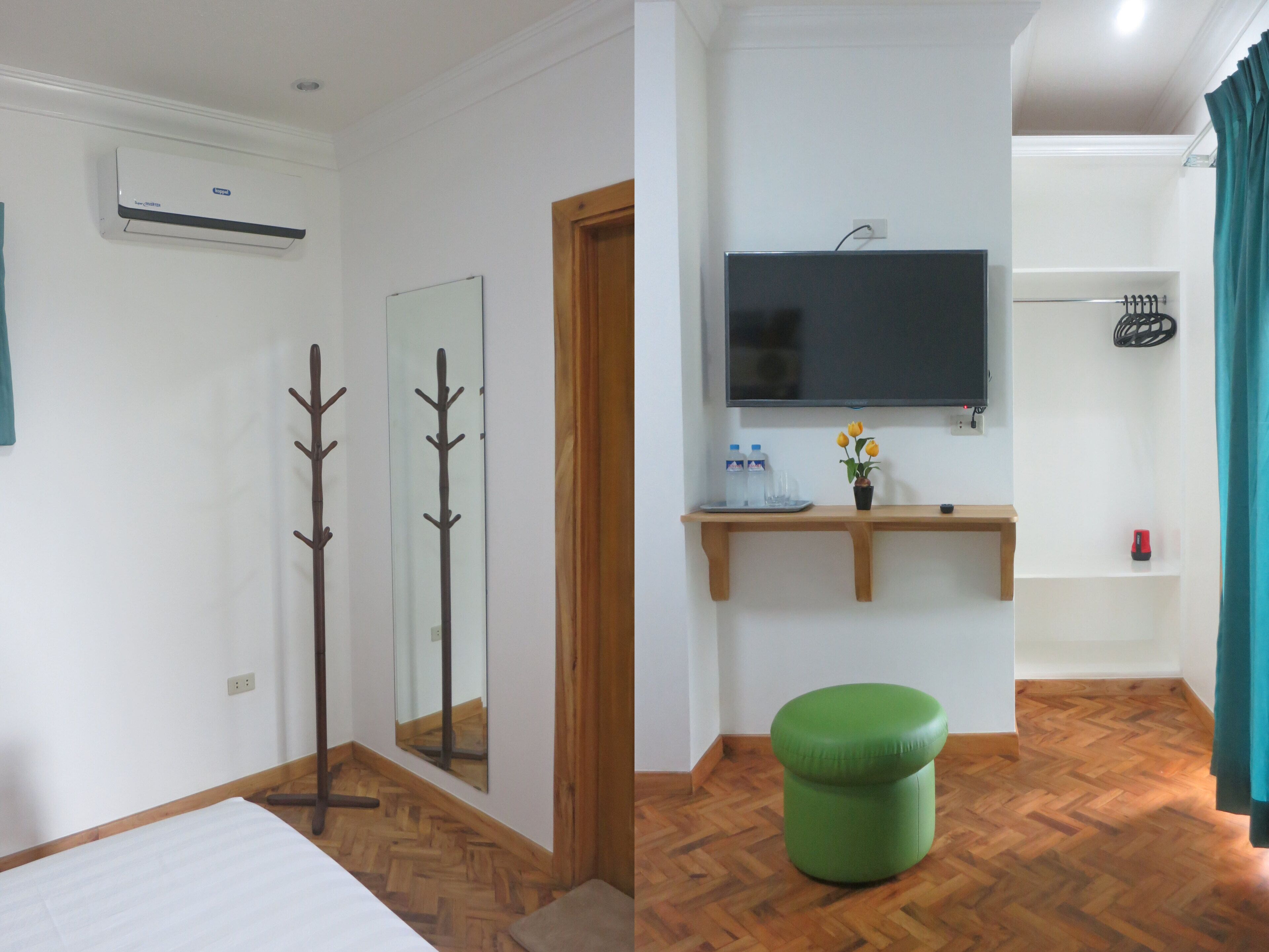 A hotel room with a bed, a wooden floor, a green ottoman, a mirror, a coat rack, a TV, and a shelf with toiletries.