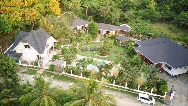 An aerial view of a residential property with multiple houses, a swimming pool, and lush greenery. - Garden Bungalows Resort (Siquijor)