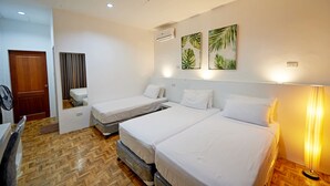 A hotel room with three single beds, a wooden floor, a wooden door, a fan, and two wall-mounted air conditioning units. - Garden Bungalows Resort (Siquijor)