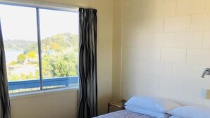 Une chambre d’hôtel avec un grand lit, une fenêtre avec des rideaux et une vue sur la verdure.