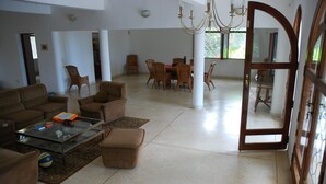 Uma sala de estar ampla com sofá, mesa de centro e área de jantar com cadeiras e mesa.