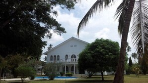 Um edifício grande e branco com fachada simétrica, janelas em arco e uma entrada central.