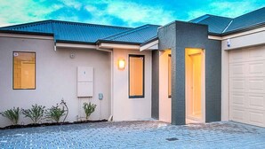 Une maison moderne avec un garage, une allée et un petit jardin.