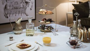 Une table de petit-déjeuner dressée avec une variété de viennoiseries, une carafe de jus de fruits et un chandelier.
