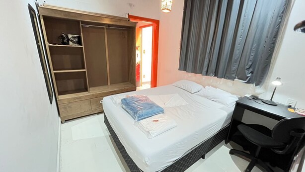 Quarto com cama, escrivaninha e guarda-roupa.