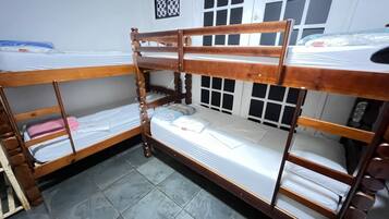 Dormitorio con literas, decoración de pared a cuadros y una ventana con persianas.