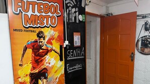 Quarto com uma porta identificada como 'FUTEBOL MISTO' e um pôster de um jogador de futebol.