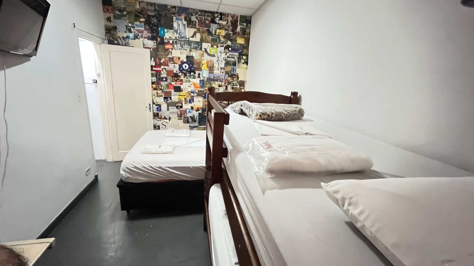 Una habitación con dos camas, una pared decorada con fotografías y un televisor a la izquierda.