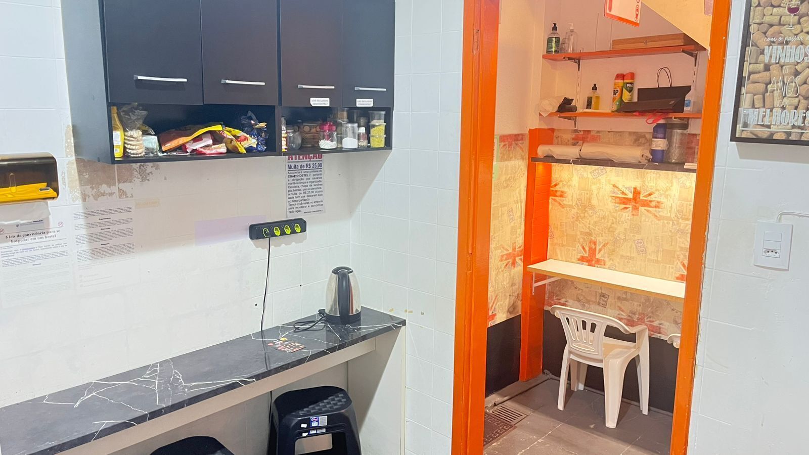 Un angolo cottura compatto con un piano di lavoro in marmo, un bollitore e un piccolo cestino.