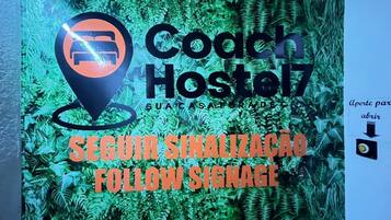 A sign for Coach Hostel with a location marker and a follow signage instruction.