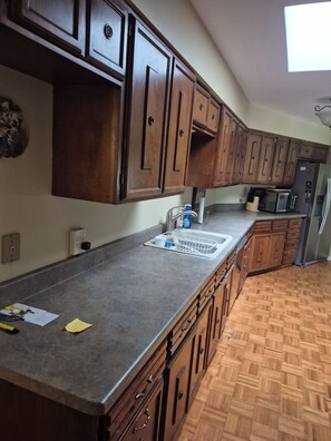 Una cocina con armarios de madera, un refrigerador de acero inoxidable y un microondas.