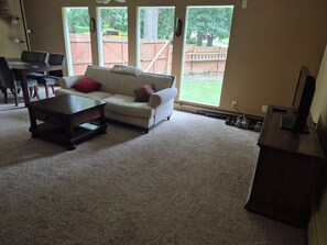A living room with a white sofa, a coffee table, and a TV on a stand.