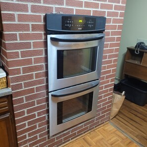 Una cocina con pared de ladrillo, horno doble y encimera de madera.
