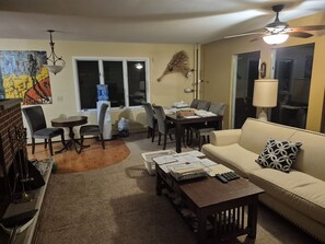 A living room with a sofa, coffee table, and dining area with chairs and a table.