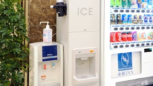 Un distributeur automatique contenant une bouteille de Coca-Cola et un flacon de gel hydroalcoolique.