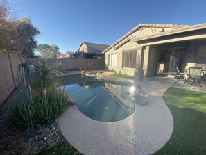 Ein Garten mit Schwimmbad, Terrasse und einem Haus.
