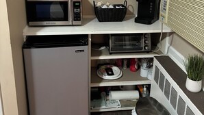 Kompakti keittokomero, jossa on mikroaaltouuni, leivänpaahdin ja jääkaappi. Siellä on myös hylly koriste-esineille ja kyltti, jossa lukee: ”Tänään on hyvä päivä, ja siitä tulee hyvä päivä.”