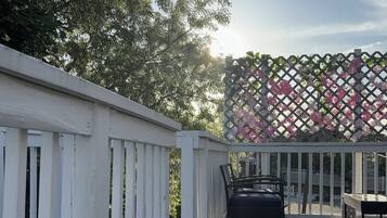 Un pontile in legno con ringhiere bianche e una struttura a griglia decorata con fiori rosa.