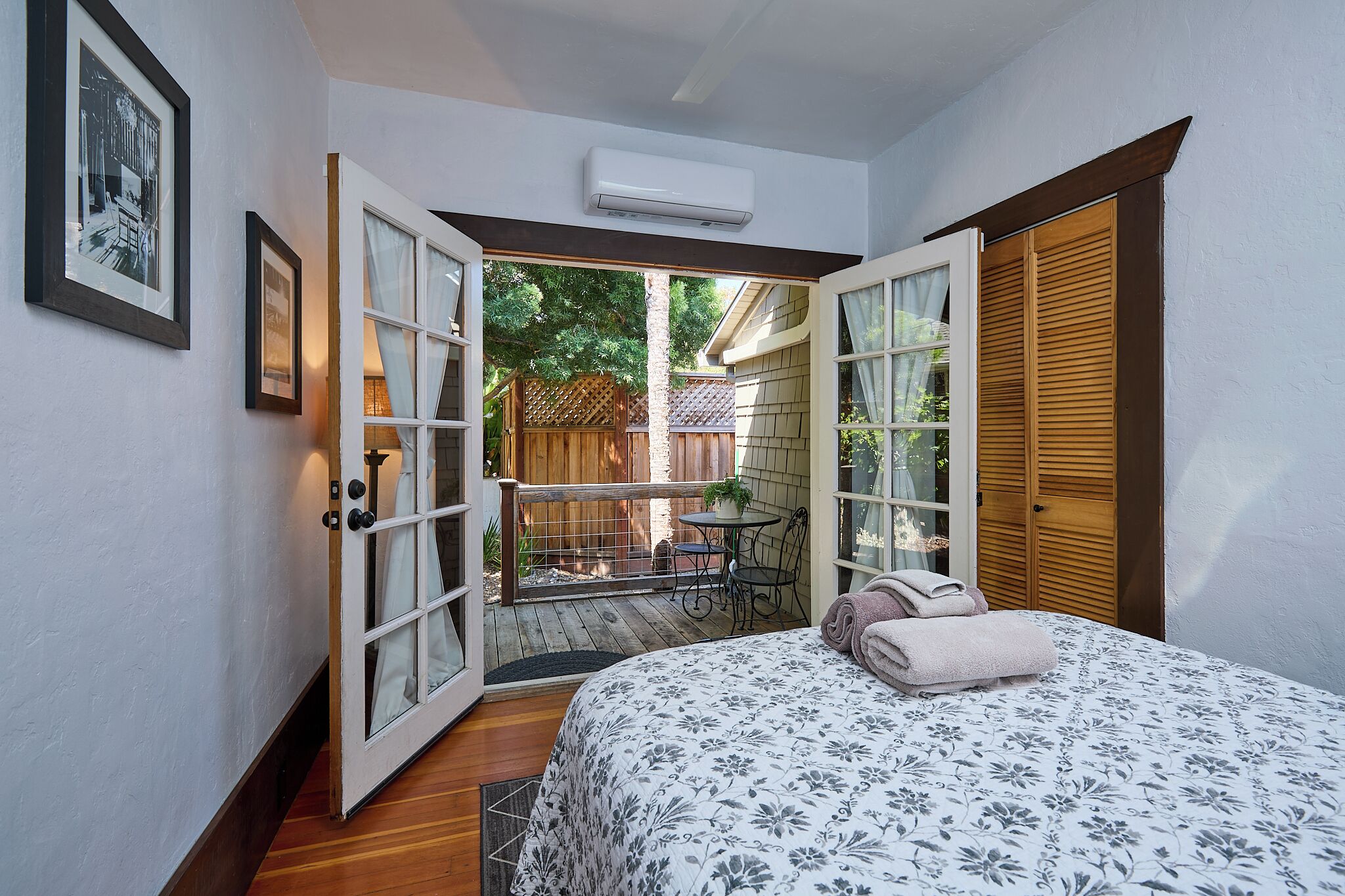 Um quarto com cama, janela e porta aberta para um pátio.