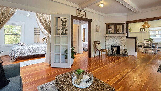A spacious living room with a fireplace, wooden flooring, and a cozy seating area.