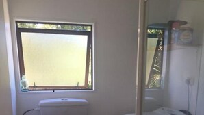 Un bagno compatto con il water, un lavandino piccolo e una cabina doccia in vetro.