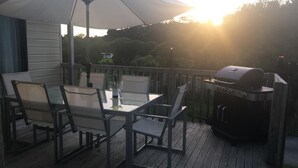 Una terrazza esterna con tavolo e sedie, un barbecue e un ombrellone grande.