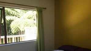 Una camera da letto con un letto, una finestra con tende e vista sul verde all'esterno.