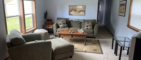 A living room with a sofa, armchair, coffee table, and a ceiling fan.