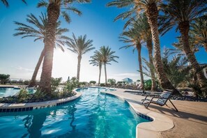 Una piscina con palmeras y sillas de descanso.