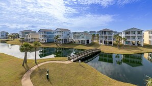 Una zona residencial frente al agua, con varias casas, un pequeño puente y un estanque.