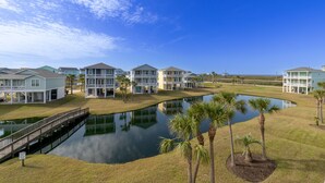 Un resort con varias edificaciones, un puente sobre un estanque y palmeras.