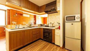Una cucina con mobili in legno, fornello, forno, microonde e frigorifero.
