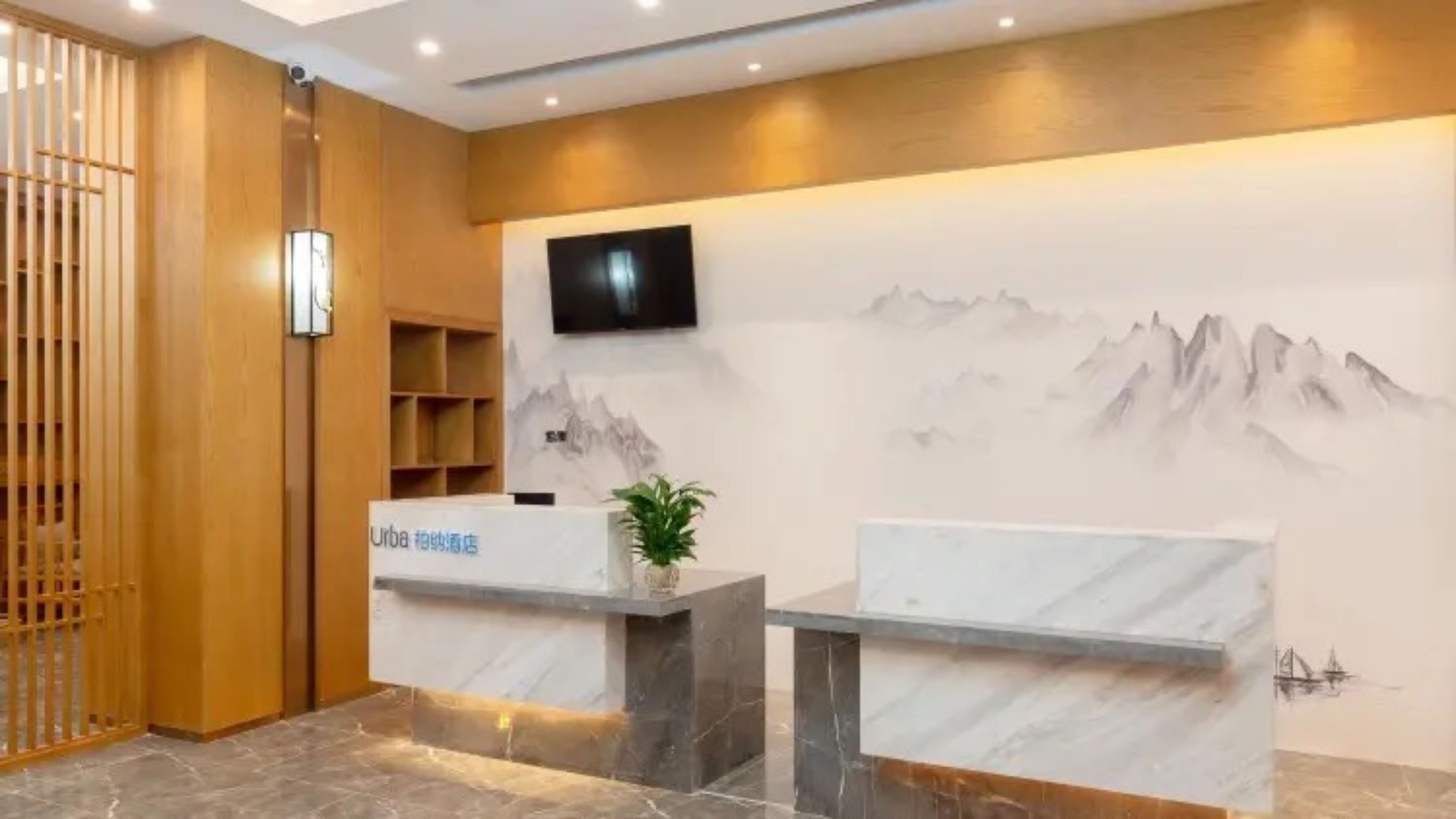 A reception desk with a modern design, a flat-screen TV mounted on the wall, and a decorative mountain painting.