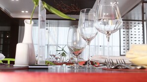 A dining table with a vase of green foliage, three wine glasses, and a white candle holder. - Sealong Bay ZhongQi Conifer Hotel (Prey Nob)