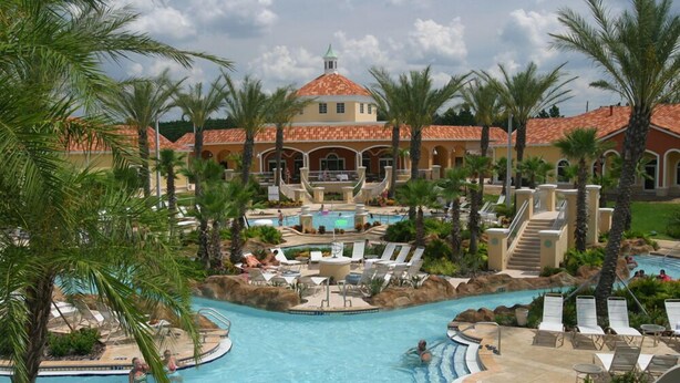 Ein Resort mit großem Pool, Palmen und einem Gebäude mit rotem Ziegeldach.