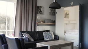 A modern living room with a sofa, a coffee table, and a hanging light fixture. - Bungalowpark It Wiid by Interhome (Eernewoude)