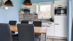 A modern kitchen with white cabinets, a built-in oven, and a window with a view of trees. - Bungalowpark It Wiid by Interhome (Eernewoude)