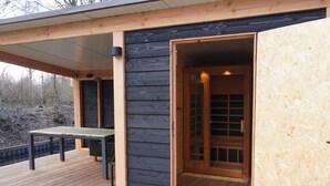 A wooden deck with a table and chairs, a covered area, and a wooden door leading inside. - Bungalowpark It Wiid by Interhome (Eernewoude)