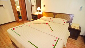 A hotel room with a large bed, a bedside table, a lamp, and a mirror. - Kuri Beach View Inn (Omadhoo)
