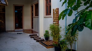 A covered outdoor area with a wooden staircase leading to a door, potted plants, and a wall-mounted charging station. - Kuri Beach View Inn (Omadhoo)