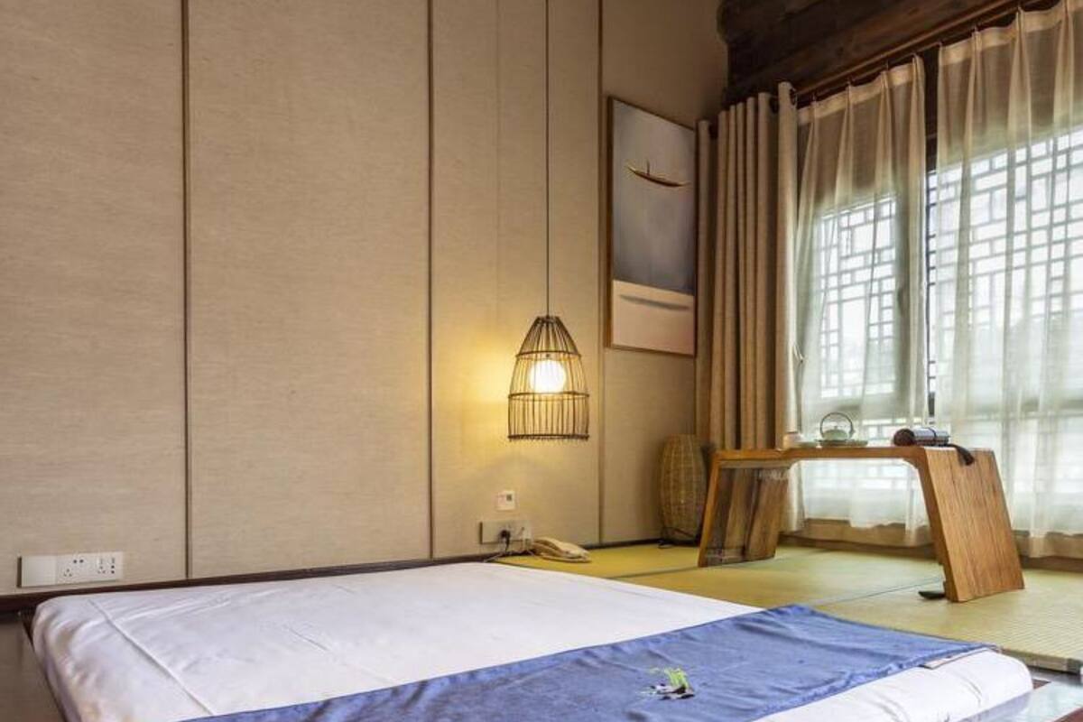 A hotel room with a large bed, a bedside table, a lamp, and a window with curtains.