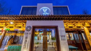A hotel entrance with traditional Chinese architectural elements, a sign with Chinese characters, and a modern building in the background. - Floral Hotel Yun Jing He Yuan Haidong (Haidong)